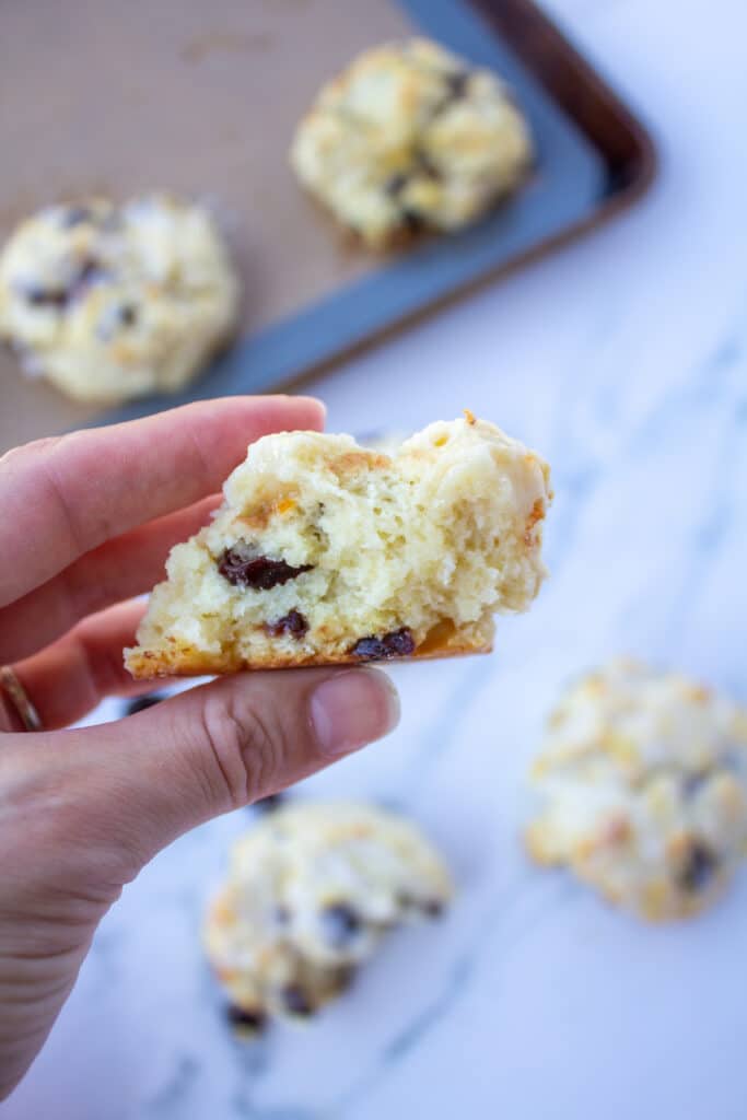 a scone with a bite taken out held in the air by a hand