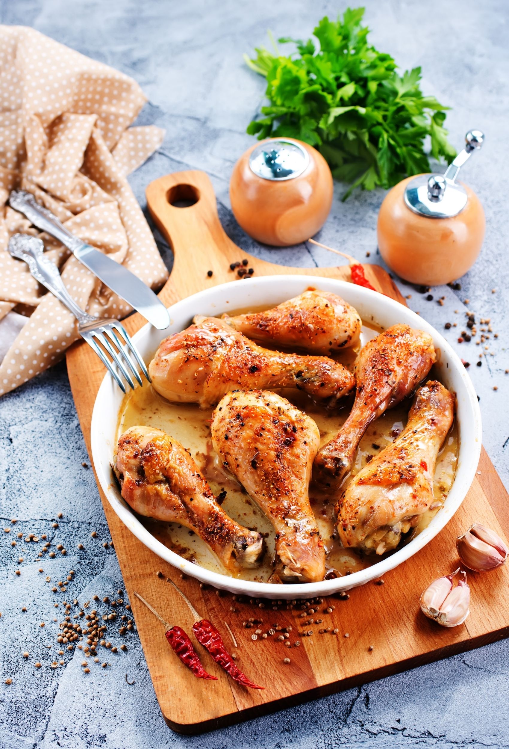 cooked chicken legs in a plate on a cutting board