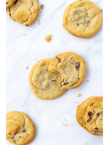 cookies spread out on a white surface with one cookie taken a bite out of