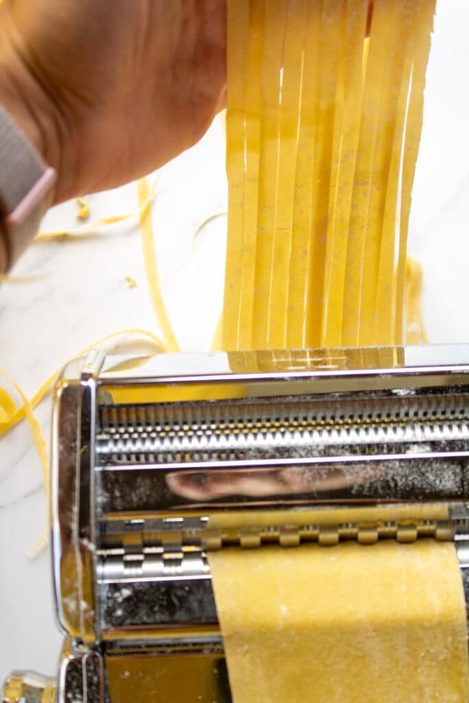 cut pasta going through a pasta machine