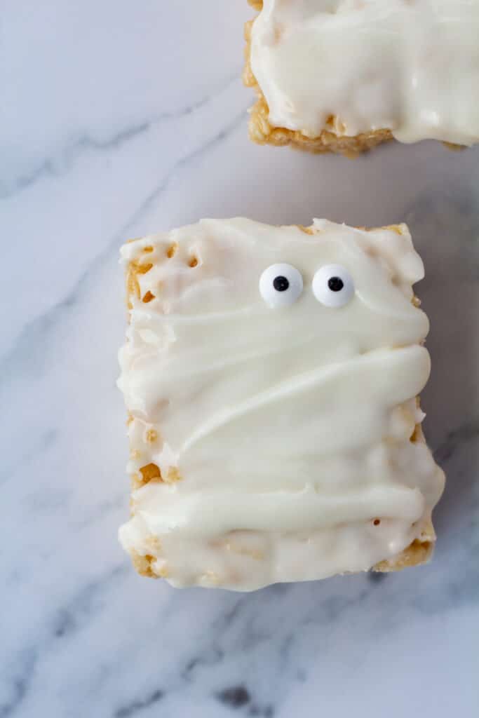 One mummy rice crispy treat with googly eyes on a white marble surface