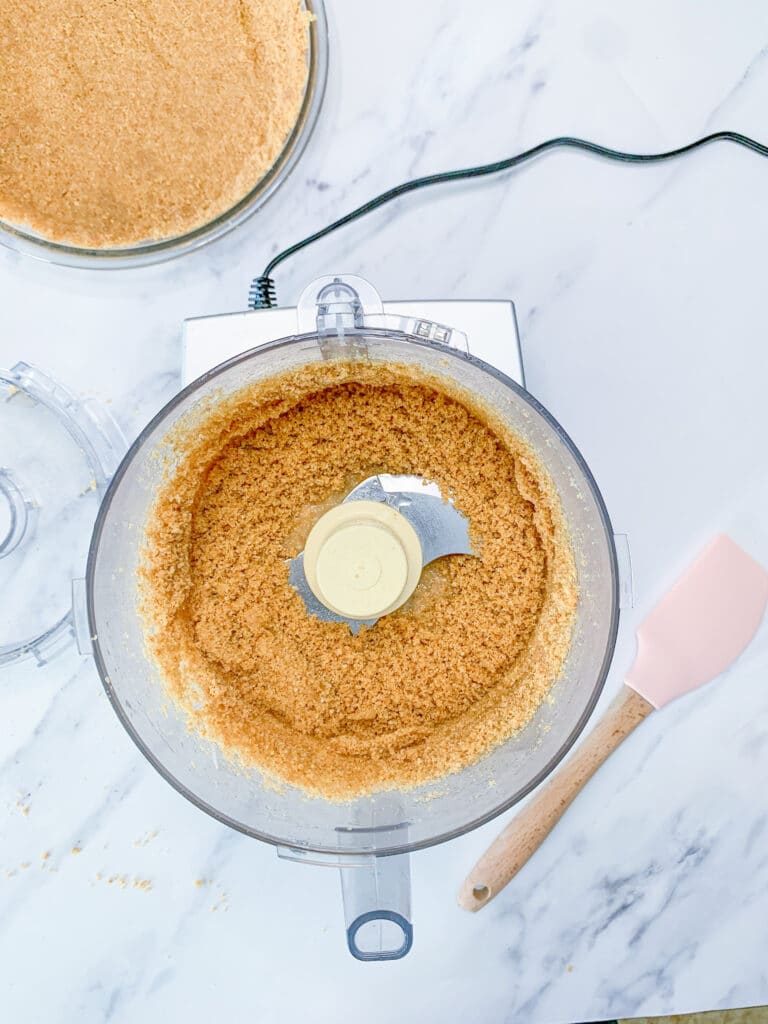 crackers, sugar, and butter being mixed with a food processor