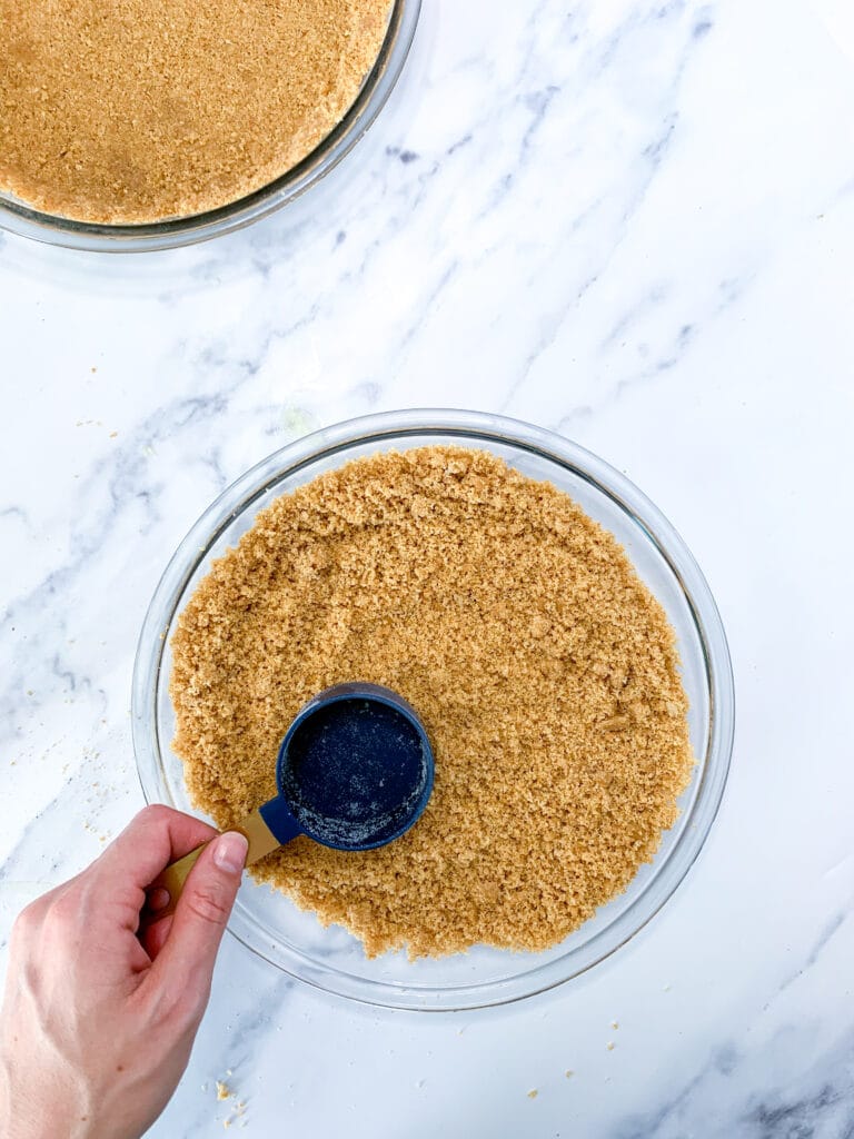 mixture being packed down with a blue measuring cup