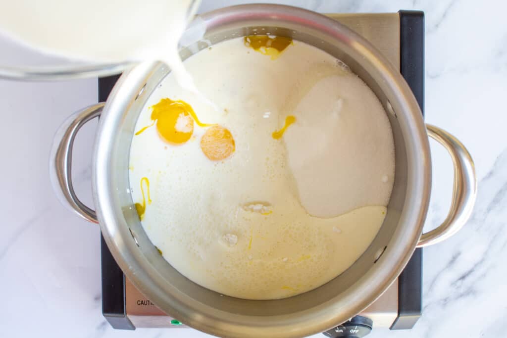 milk being poured into a pot with other ingredients