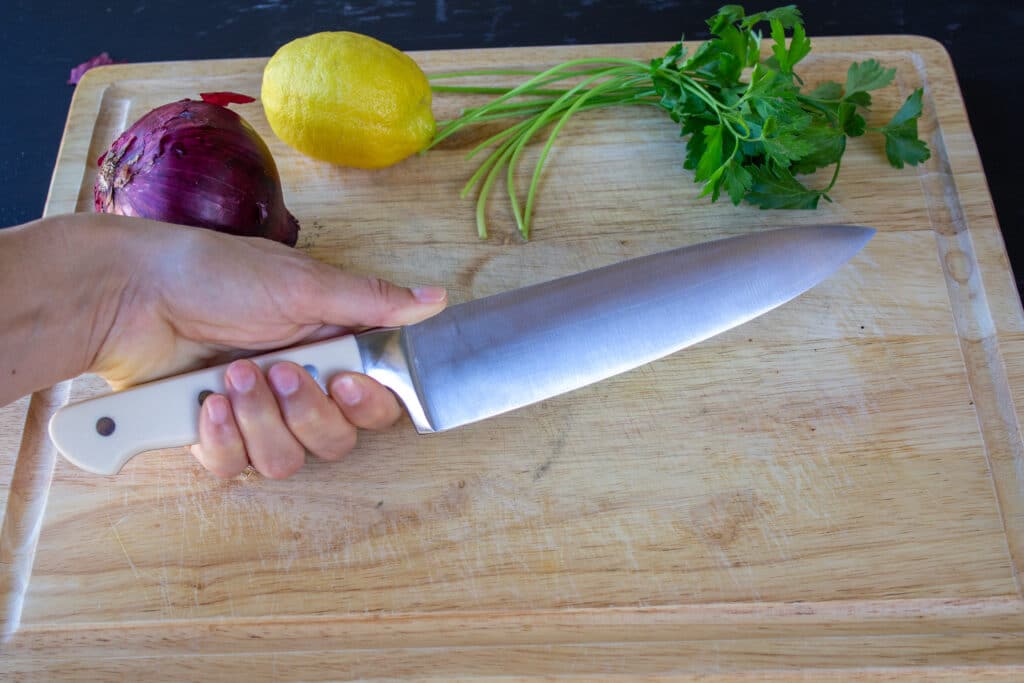 hand holding a chef's knife with the thumb on top