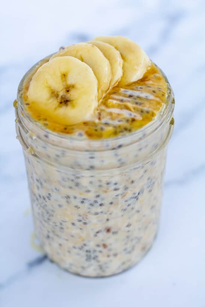 straight on view of oats in a jar topped with bananas and honey