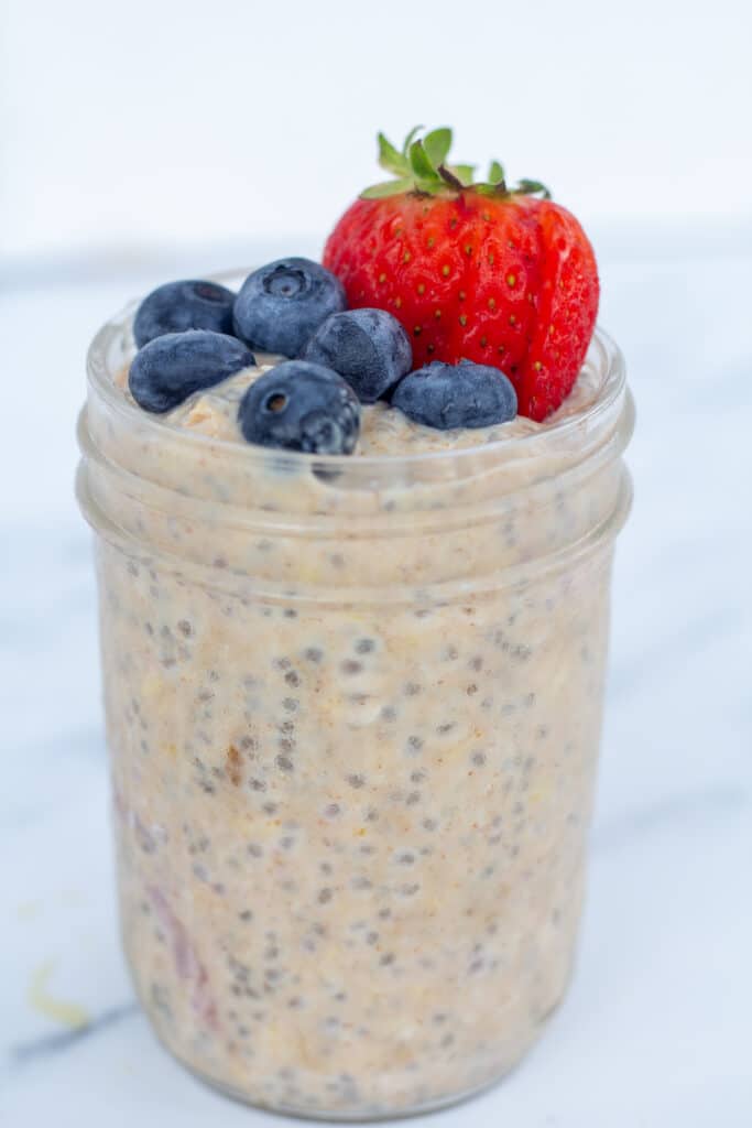 straight on view of oats in a jar topped with strawberries and blueberries