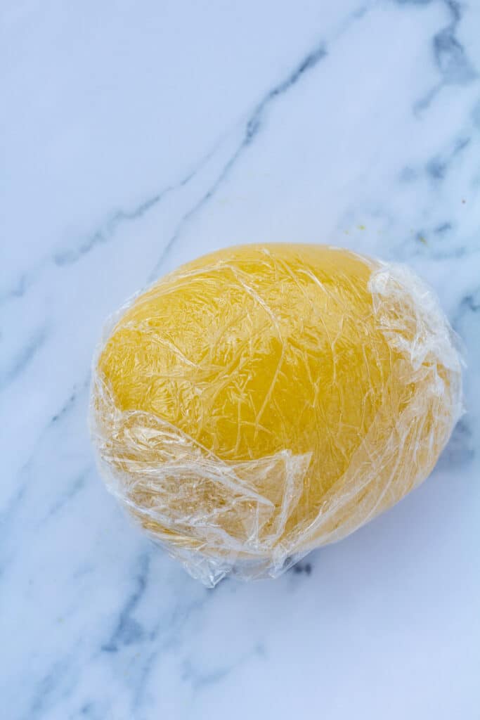 a ball of pasta dough wrapped in plastic wrap