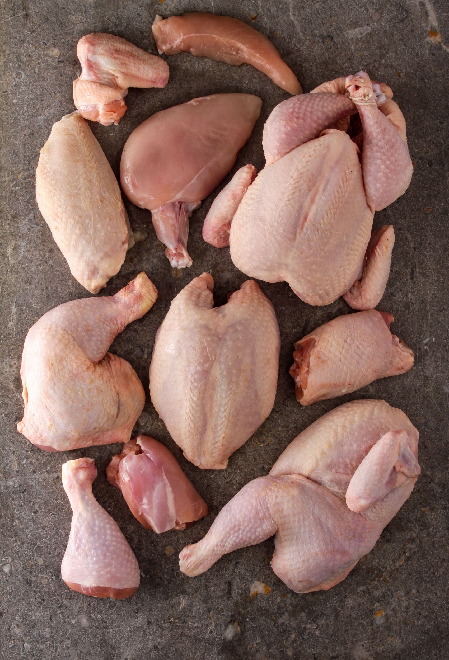 pieces of a whole chicken layed out on a gray background
