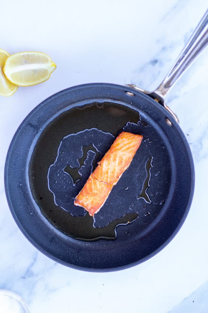 One piece of salmon in a saute pan