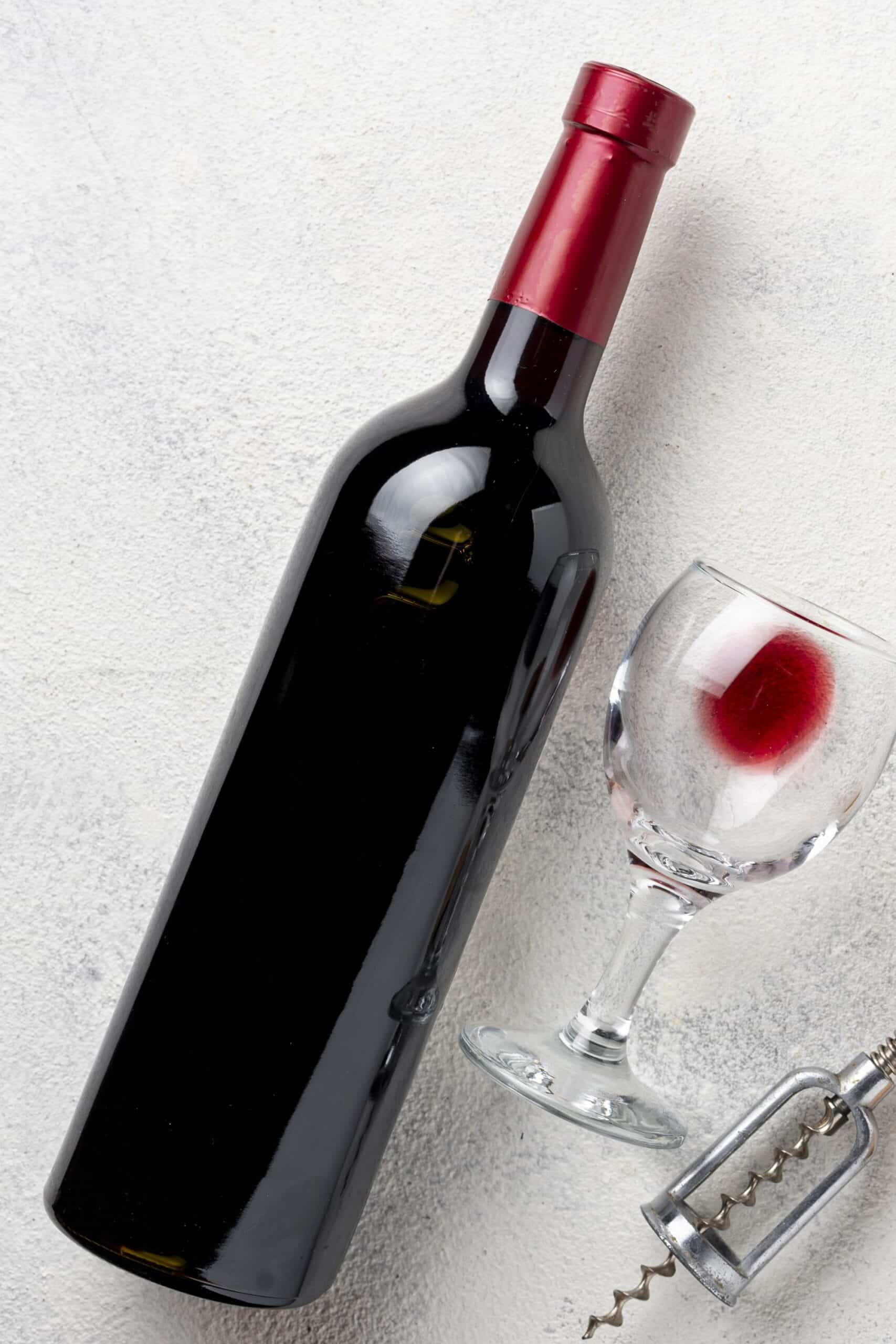 red wine bottle laying down next to a glass