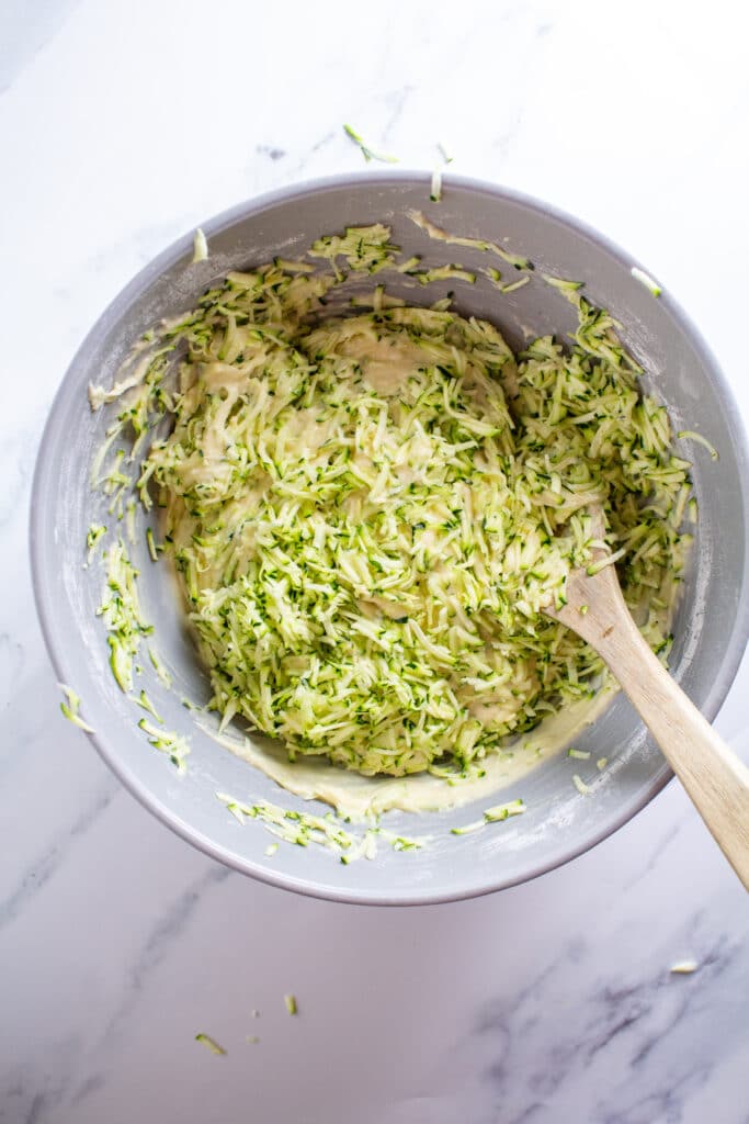 A bowl of batter with the zucchini half mixed in