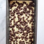 Bread batter in a loaf pan with chocolate chips on top