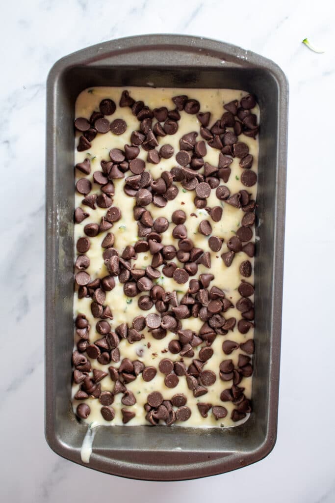 Bread batter in a loaf pan with chocolate chips on top