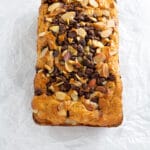 A whole loaf of bread with chocolate chips and sliced almonds on a white background