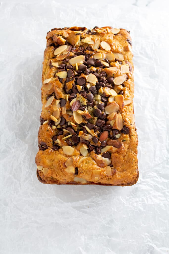 A whole loaf of bread with chocolate chips and sliced almonds on a white background