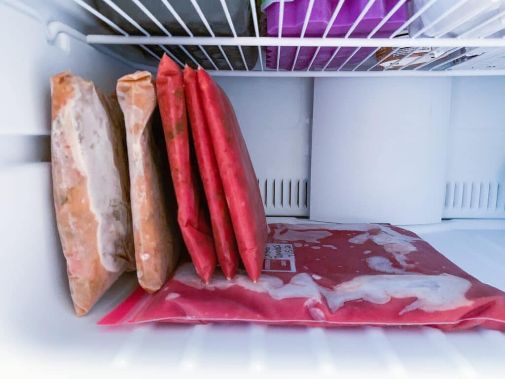 Bags filled with food frozen flat and now standing up in a freezer.