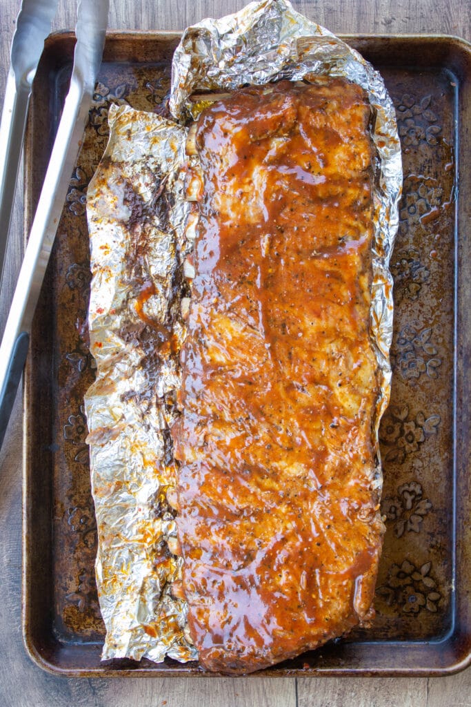 pork ribs brushed with BBQ sauce on a baking sheet