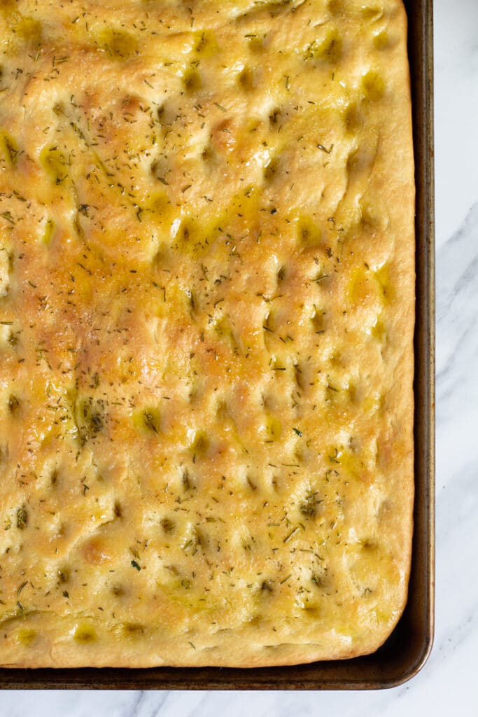 the corner of baked focaccia in a pan