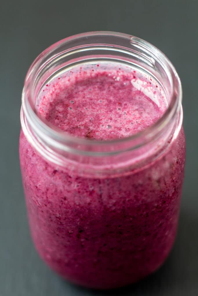 side view of a purple smoothie with honey drizzled on top