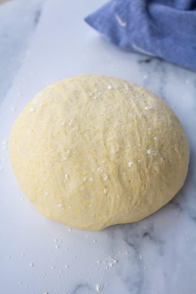 one ball of pizza dough on a marble counter