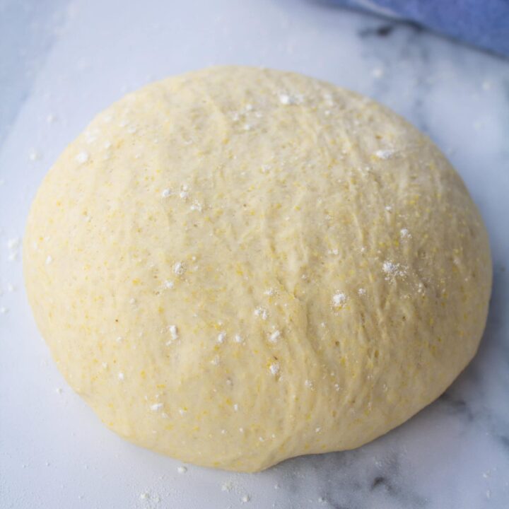 one ball of pizza dough on a marble counter