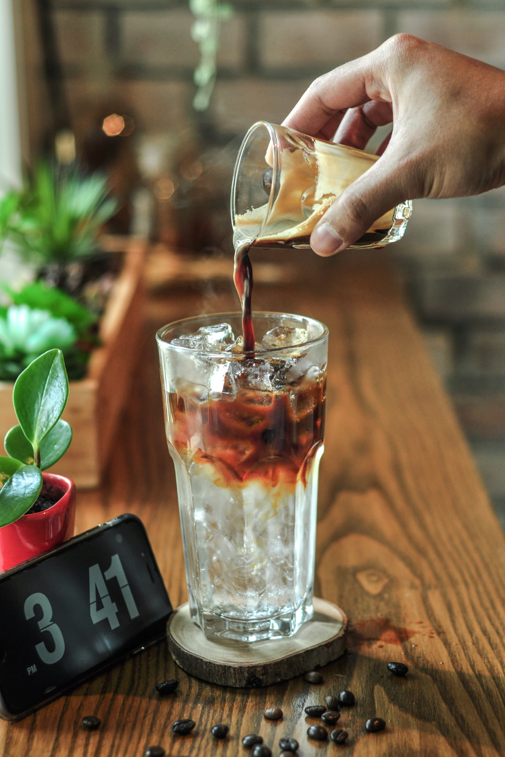 Pouring coffee over ice in a tall glass