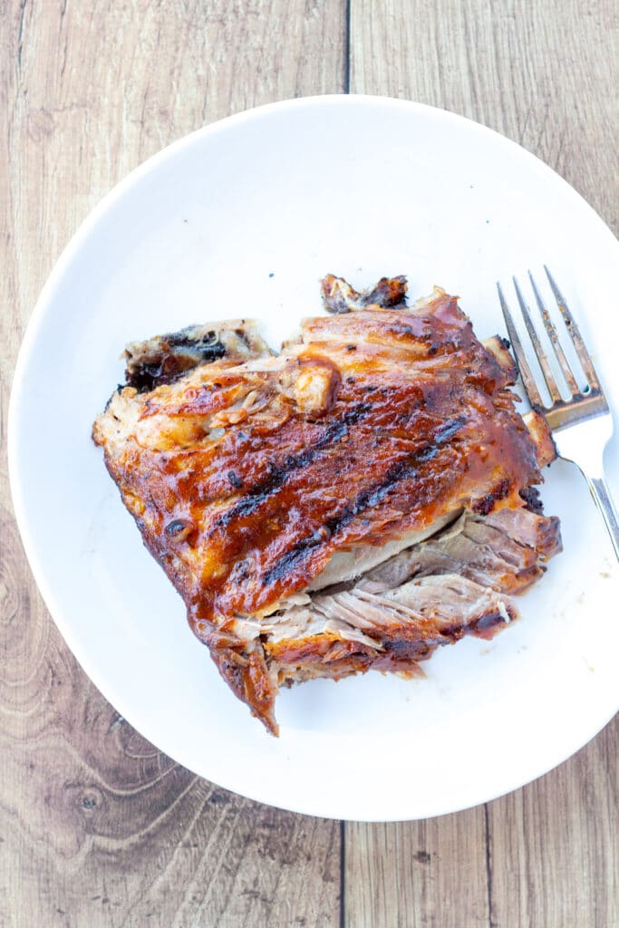 a single portion of ribs on a small white plate with a fork