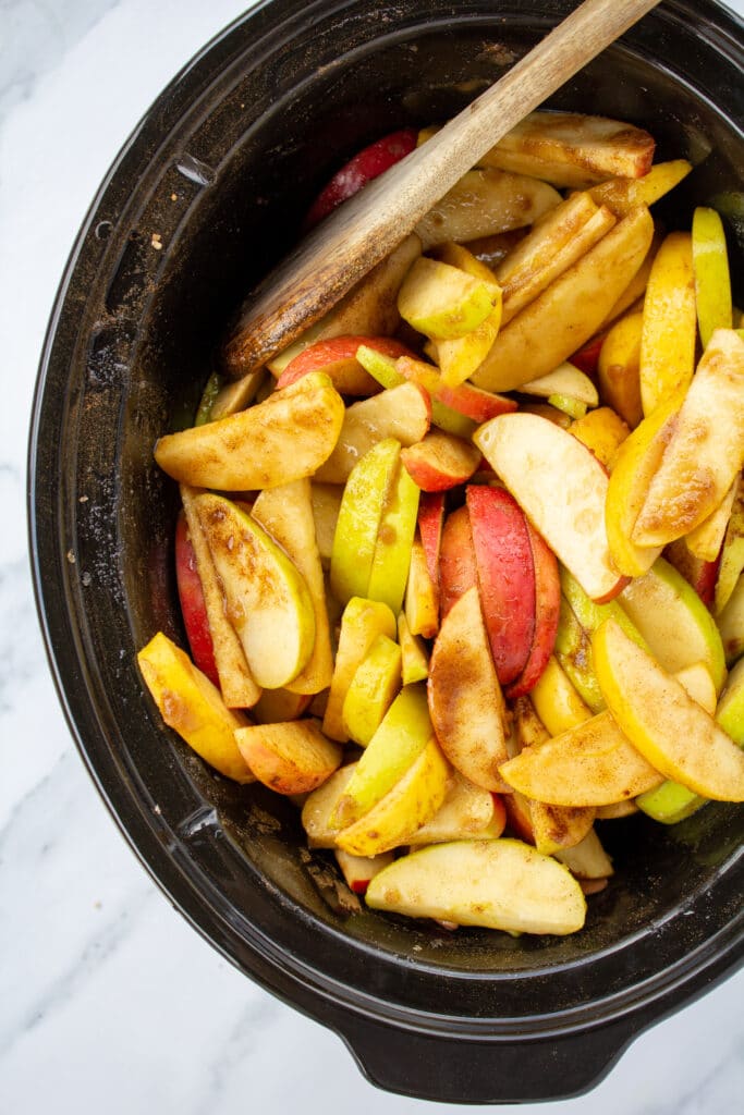 crockpot-full-of-coated-apples-and-a-wooden-spoon-sitting-on-a-marble-counter