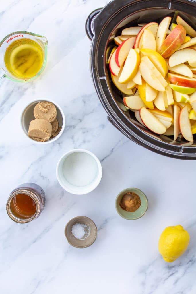 ingredients-for-apple-butter-next-to-a-slow-cooker-filled-with-sliced-apples