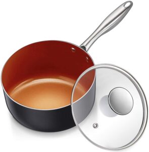 A copper and black medium sauce pot with a glass lid sitting on the side