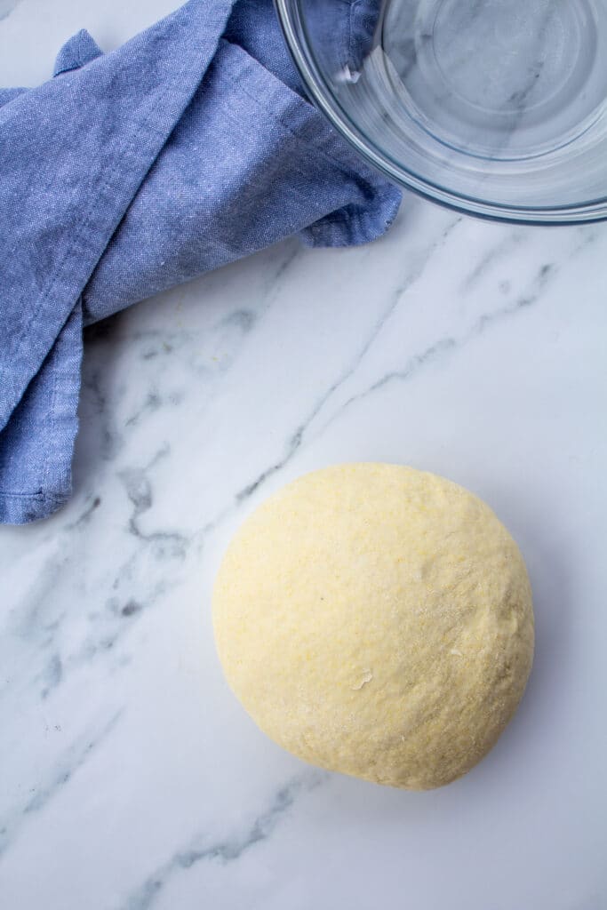 ball of dough on a marble counter next to a blue napkin