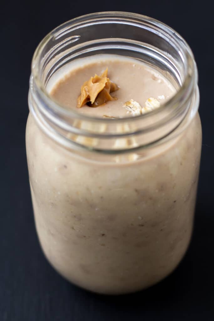 side view of a tan smoothie with peanut butter and oats on top