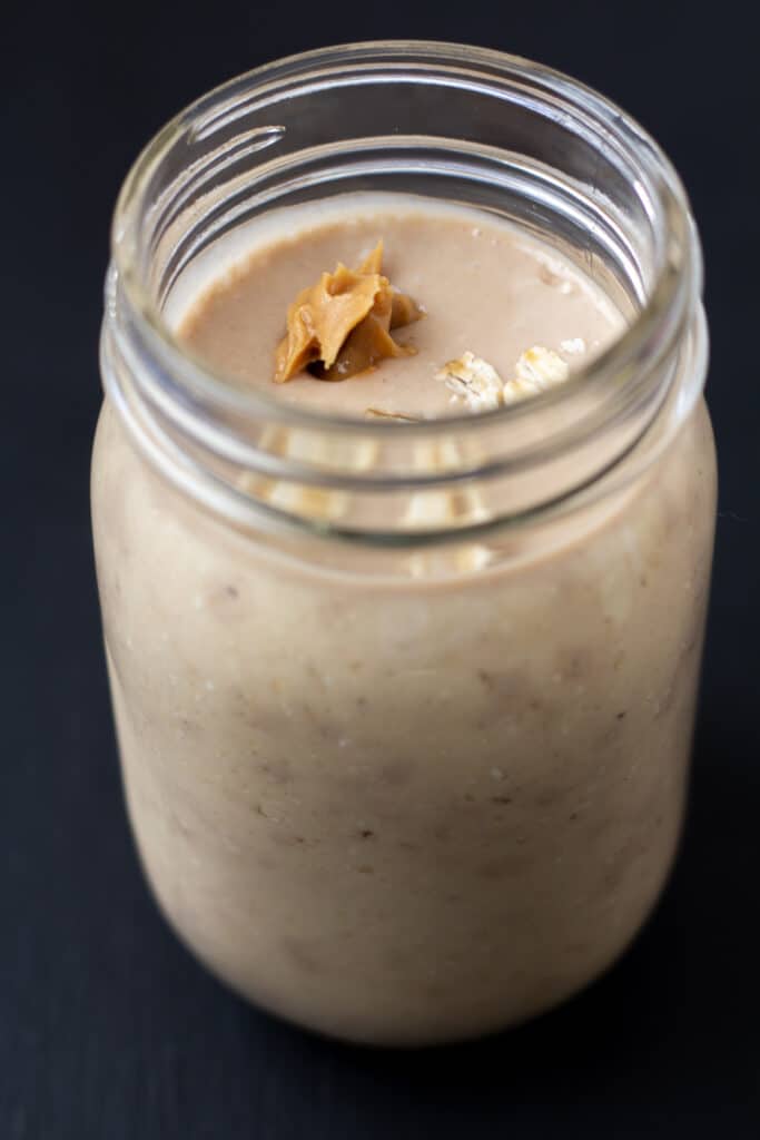 side view of a tan smoothie with peanut butter and oats on top