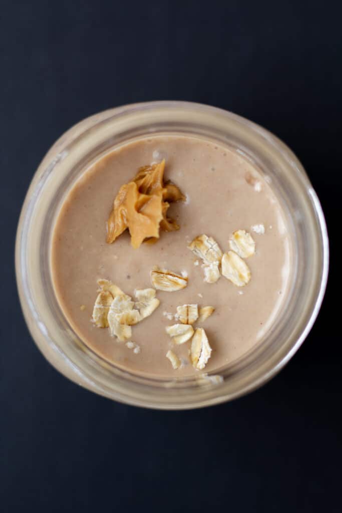 overhead view of a tan smoothie with a dollop of peanut butter and oats on top