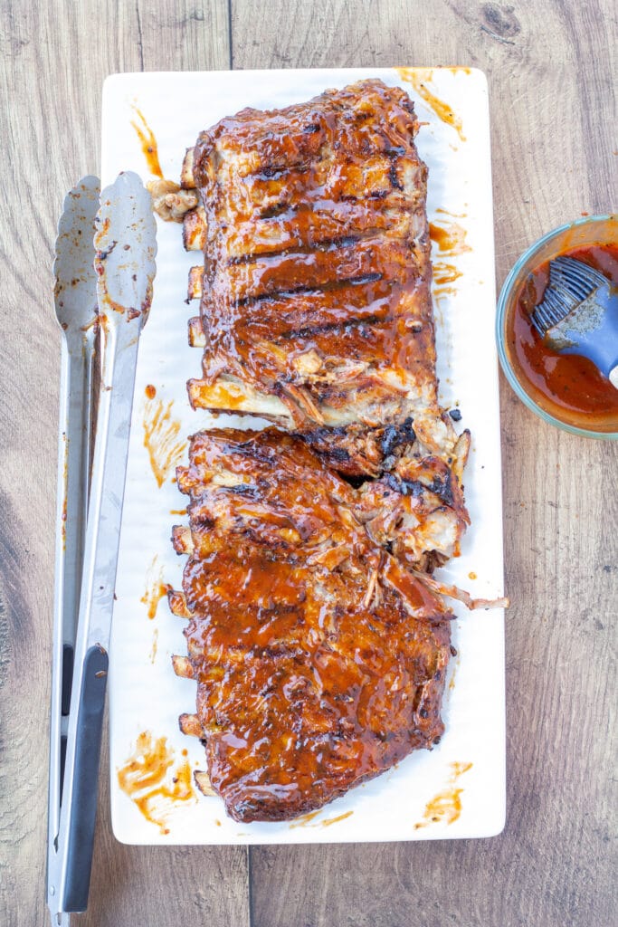 grilled BBQ pork ribs on a white plate brushed with sauce 