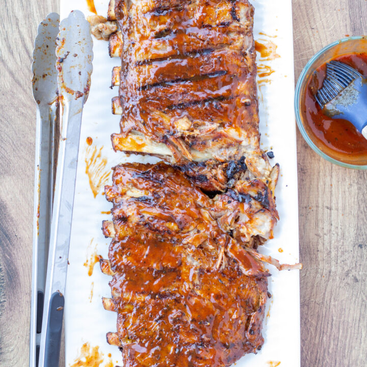 grilled BBQ pork ribs on a white plate brushed with sauce