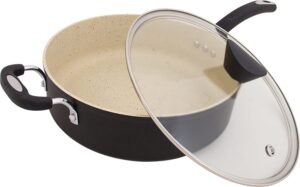 A large stone sauce pan with handles on both sides and a glass lid sitting to the side 