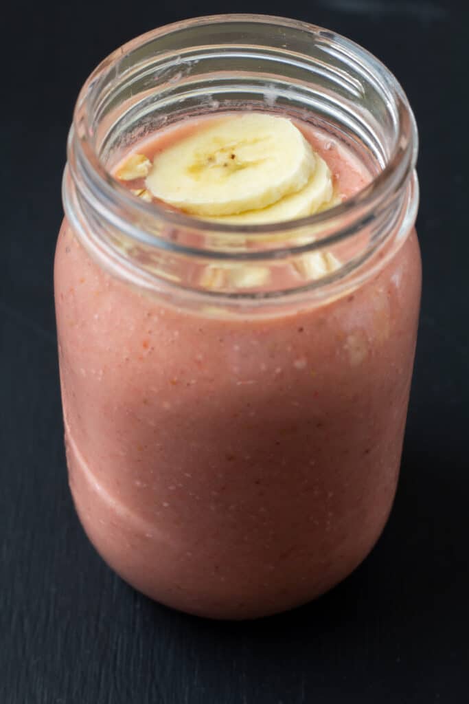 side view of a red smoothie with slice bananas and oats on top