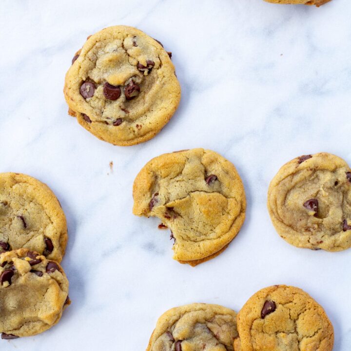 cookies spread out on a white surface with one cookie taken a bite out of