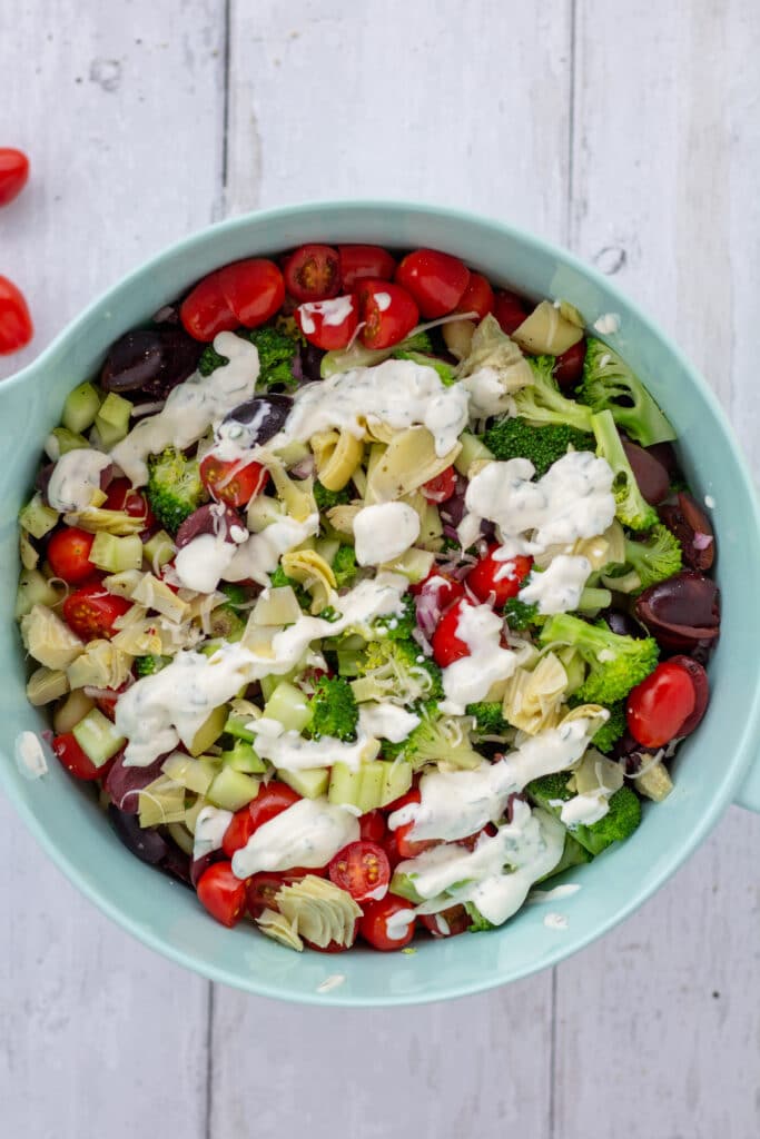 blue bowl of chopped veggies drizzled with ranch dressing