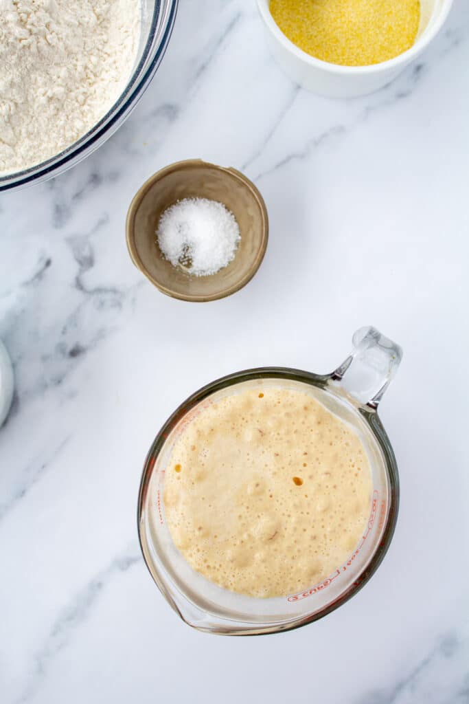 rising yeast on a marble counter surrounded with dough ingredients